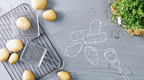 Gezeichnete Kroketten neben rohen Kartoffeln und Frittierkörben.