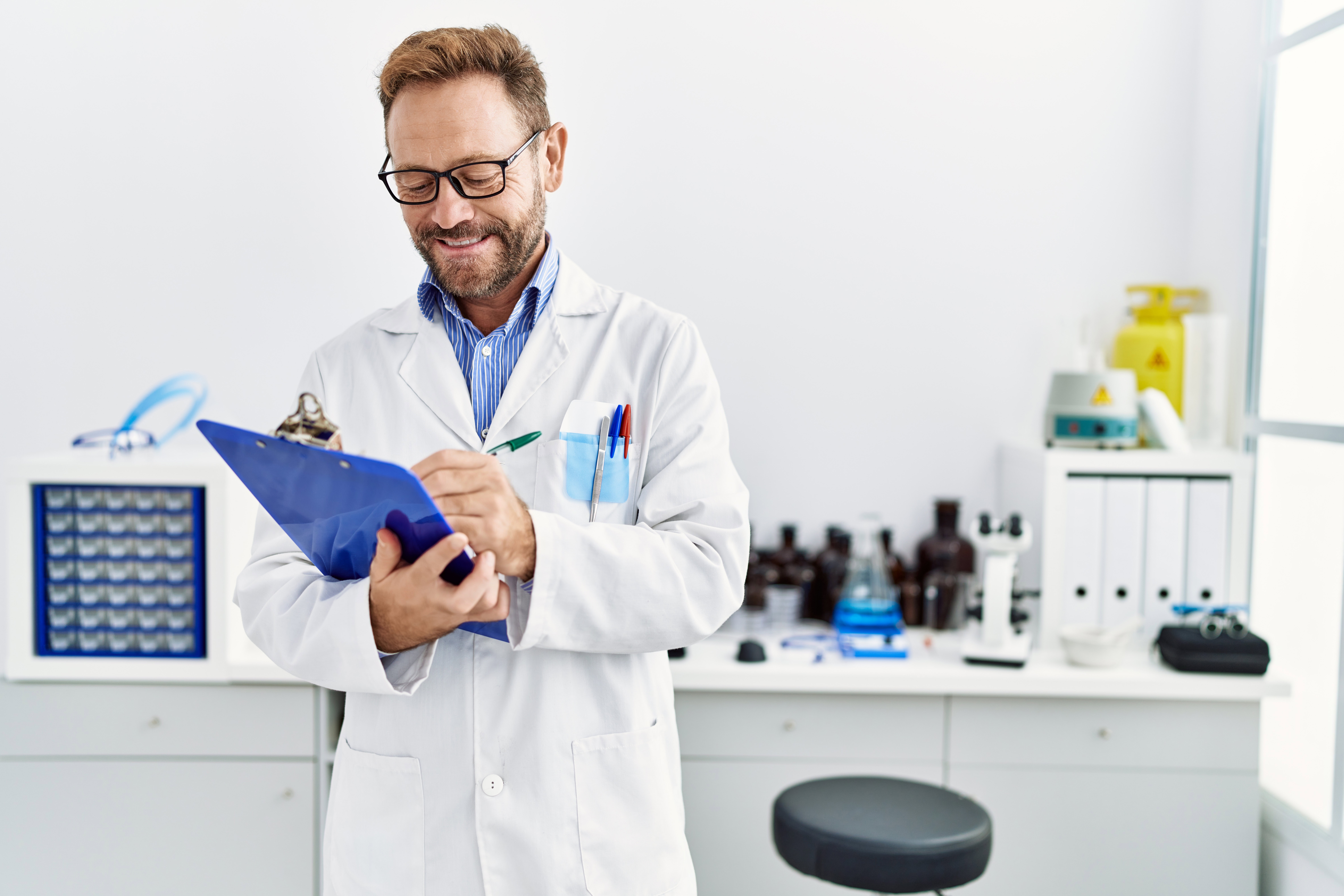 middle age hispanic man smiling confident wearing scientist uniform laboratory